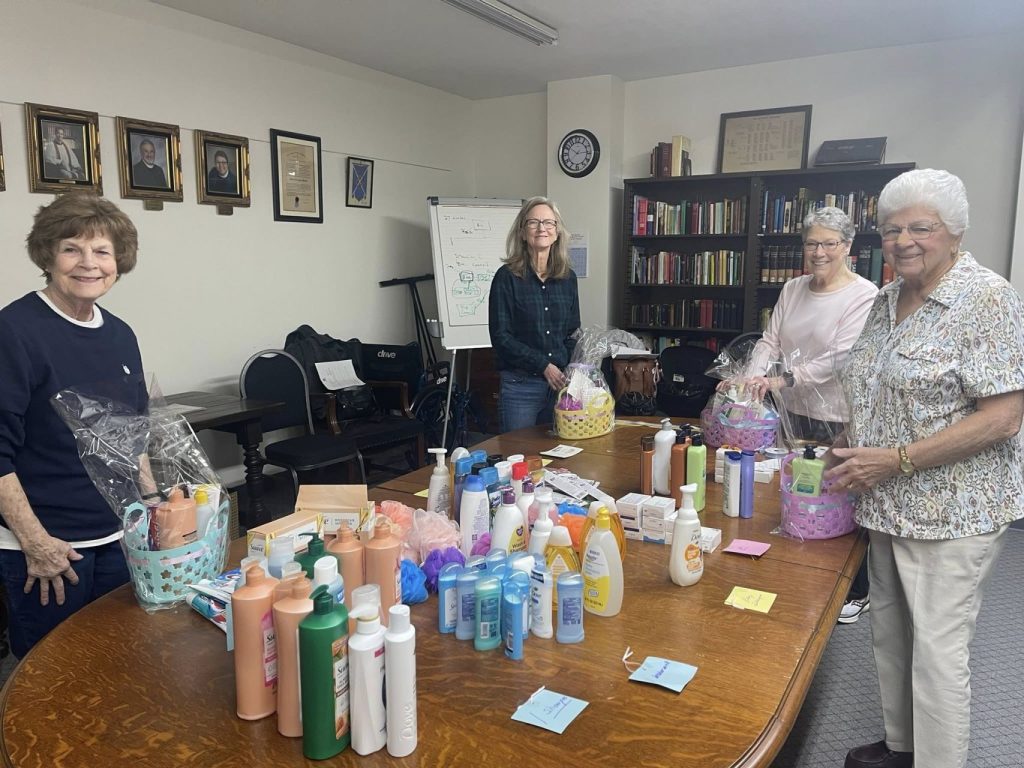 Four women around table on which is an assortment of health and beauty products